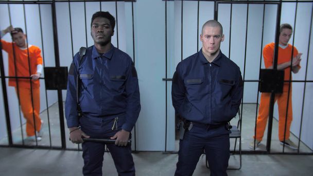 Wachters staan op de achtergrond van gevangeniscellen - Foto, afbeelding