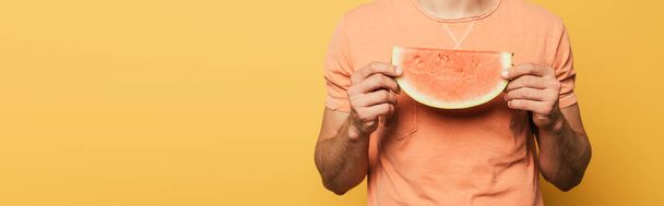 cropped view of young man holding slice of ripe watermelon on yellow background, panoramic orientation - Foto, Imagen