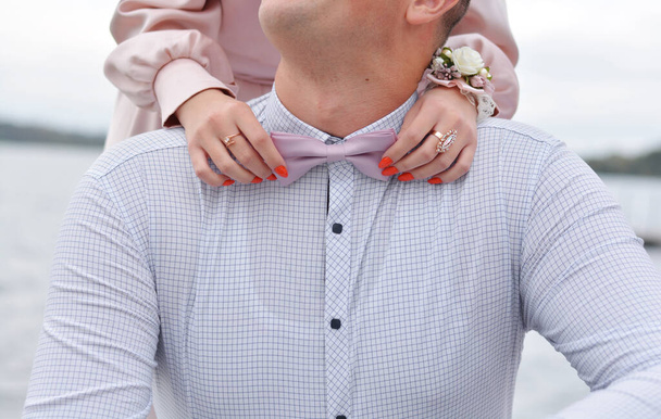 Hombre el novio en un traje de boda con mariposa. Manos de mujer sujetando accesorios. Vacaciones
. - Foto, Imagen