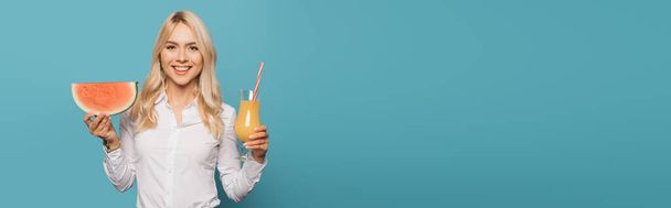 panoramic shot of smiling businesswoman holding orange juice and watermelon isolated on blue - Foto, Bild