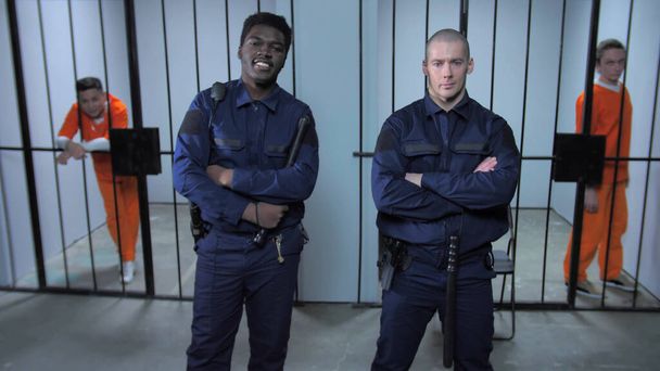 Тюремные охранники стоят возле тюремных камер
 - Фото, изображение