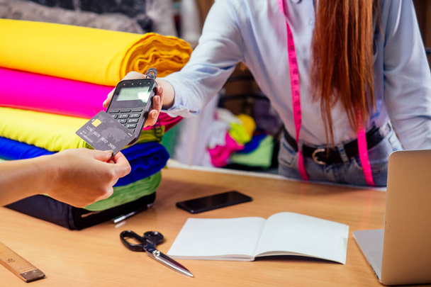 рудий імбирний касир жінка в магазині тканин, що дає жінці-клієнту білл-транзакцію
 - Фото, зображення