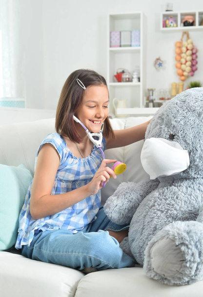  little girl  with stethoscope playing with  toy teddy  bear in facial mask - Zdjęcie, obraz