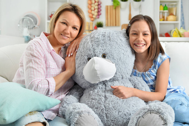  little girl and mother   with toy teddy  bear in facial mask - Foto, Bild