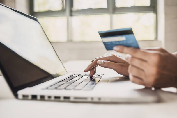 Jeune femme tenant une carte de crédit et utilisant un ordinateur portable. Shopping en ligne, profiter de la vie, concept d'argent de dépense
. - Photo, image