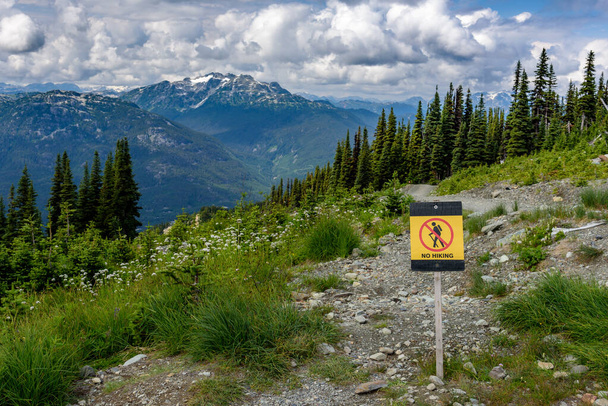 "Ei patikointia" kyltti, Alppivuorella, lumihuippuiset vuoret kauempana. Kyltti sijaitsee Whistler vuorella, Kanadassa
 - Valokuva, kuva