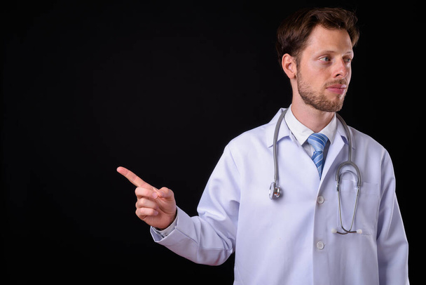 Студійний знімок красивого бородатого лікаря на чорному тлі
 - Фото, зображення