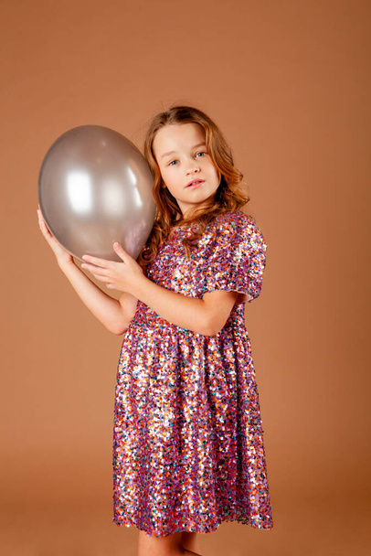 girl in a party dress holding a balloon in her hands - Photo, Image