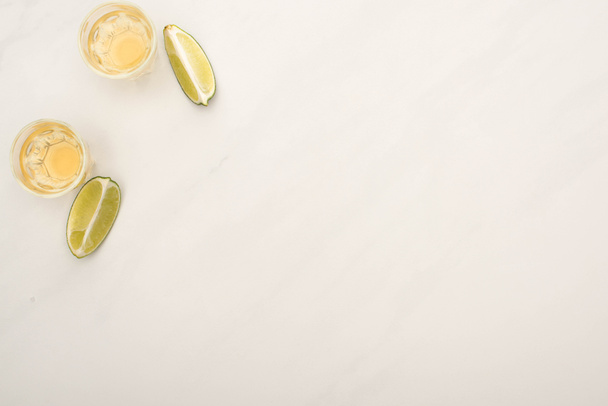 vista superior da tequila dourada com limão na superfície de mármore branco
 - Foto, Imagem