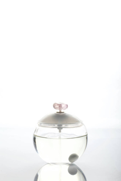 Glass ball-shaped bottle with women's perfume. On a white background. - Фото, зображення
