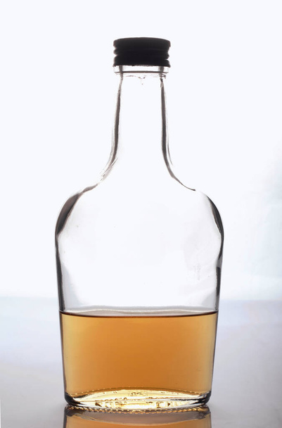 Glass transparent bottle with strong alcohol. On a white background. - Фото, изображение