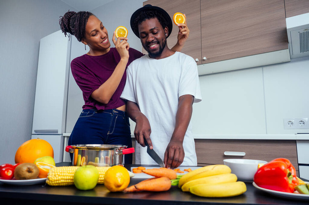 Happy african american love couple cooking fruits salad at kitchen - 写真・画像
