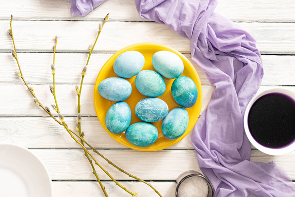 Aquamarine marble Easter eggs lie on a yellow saucer and white background. as a symbol of Easter - Foto, Bild
