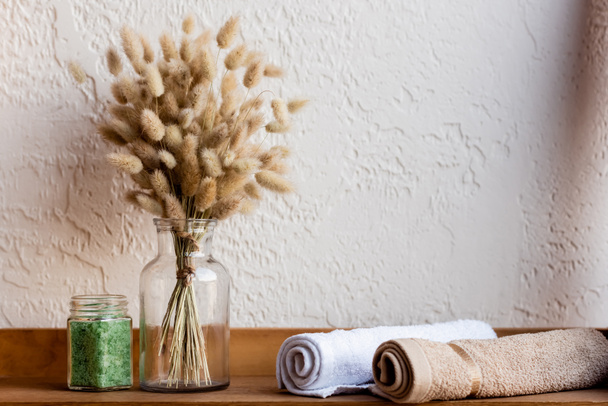 bloeiende katjes, handdoekrollen en groen zeezout in pot op houten plank  - Foto, afbeelding