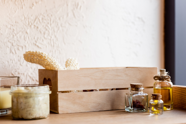 wooden box, with loofah, bottles of oil, clay mask in jar and candle on shelf  - Fotoğraf, Görsel