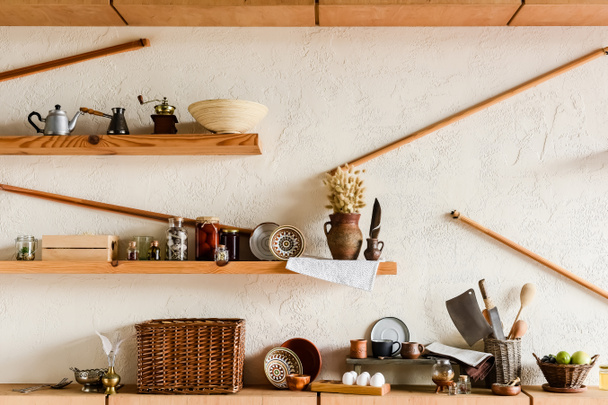 clay mugs and bowls on shelves near knifes raw eggs and tasty fruits in kitchen  - Fotoğraf, Görsel