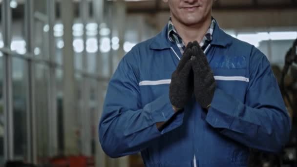Inženýr z továrny pozdravil rukama, aby projevil úctu s úsměvem šťastným v práci. Bezpečnostní přilba pomáhá chránit při práci mechanika. Bezkontaktní pozdravy pomáhají předcházet koronaviru (COVID-19). - Záběry, video