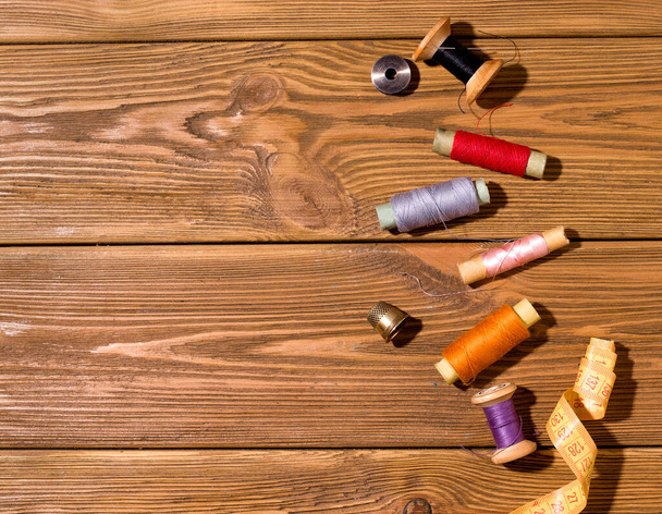Threads of different colors on a wooden table. Copy space. The concept of sewing and repairing old things - Photo, Image