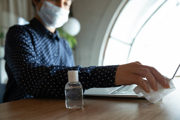 Close-up van vrouwelijke desinfectie laptop met gel sanitizer - Foto, afbeelding