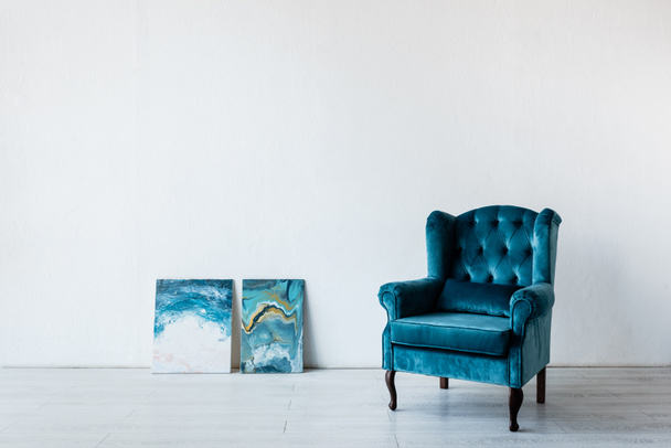 αναπαυτική πολυθρόνα κοντά σε πίνακες στο σαλόνι  - Φωτογραφία, εικόνα