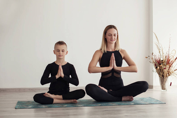 madre e figlio fare yoga in quarantena a casa (esercizi sportivi), divertirsi e trascorrere un buon tempo insieme. isolato su bianco. il concetto di uno stile di vita sano (COVID - 19
) - Foto, immagini
