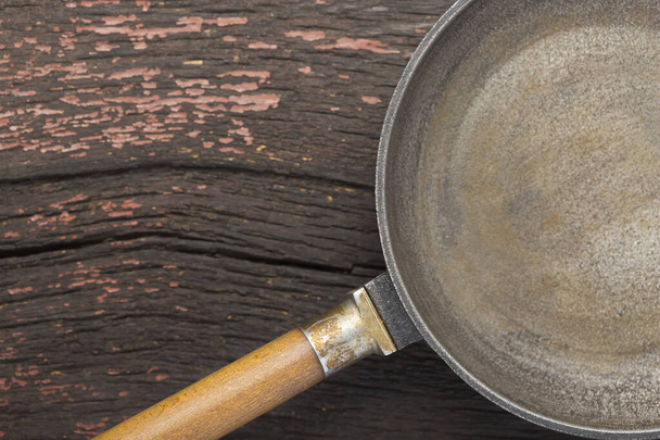 old frying pan on a wooden table. top view - Foto, afbeelding