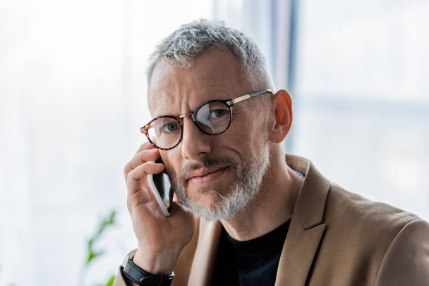 handsome and bearded businessman in glasses talking on smartphone  - Foto, imagen
