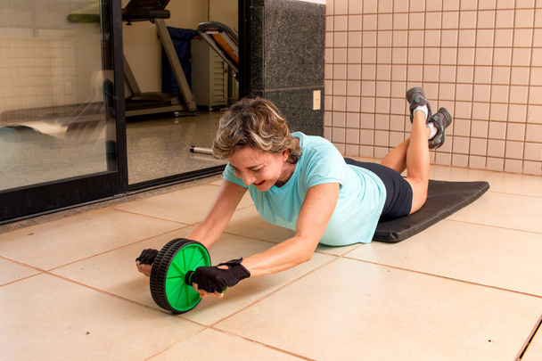 Mujer en forma haciendo ejercicio con una rueda de rodillo Ab
 - Foto, Imagen