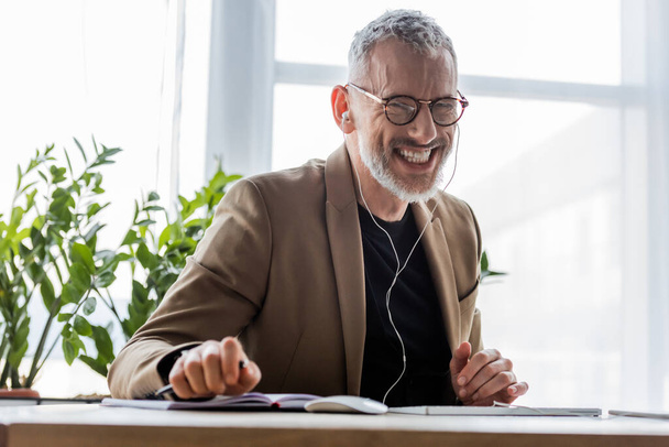 selective focus of happy businessman in earphones looking at camera  - Фото, изображение
