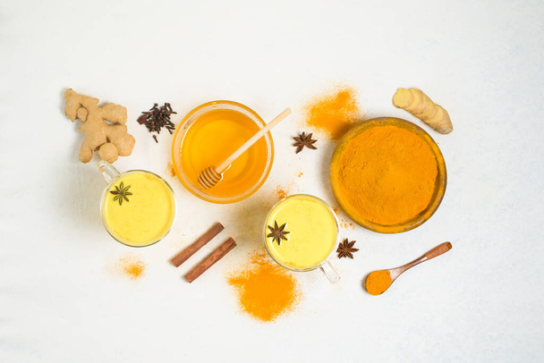 Indian traditional Golden milk with turmeric, ginger, spices, honey. healing effect of the drink. ingredients for a Golden drink on a light background. antiviral antioxidant. the view from the top. - Foto, Imagem