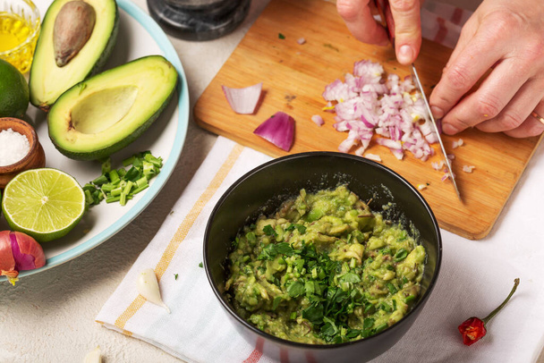 Mexikói guacamole szósz készítésének folyamata. A nő hagymát szeletel.. - Fotó, kép