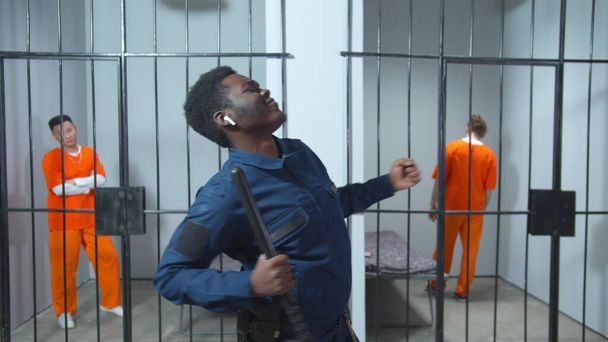 Der Gefängniswärter hört Musik über drahtlose Kopfhörer und tanzt - Foto, Bild