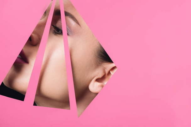 Női arc a háromszög alakú lyukak rózsaszín papír - Fotó, kép