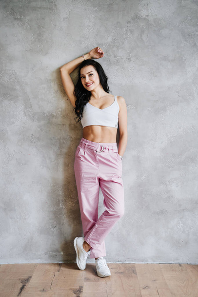 Portrait of fashionable young brunette woman dressed in pink pants, sneakers - Φωτογραφία, εικόνα