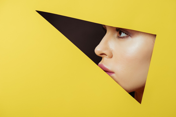 Female profile in triangular hole in yellow paper on black background - Фото, изображение