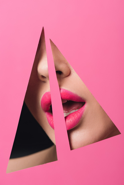 Vista ritagliata di donna con labbra rosa e bocca aperta in fori triangolari in carta su nero
 - Foto, immagini