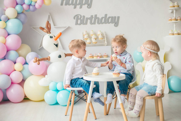 Cute little boys and girl at a table with birthday cakes at a children's party with balloons. Children's party. Balloons - Fotografie, Obrázek