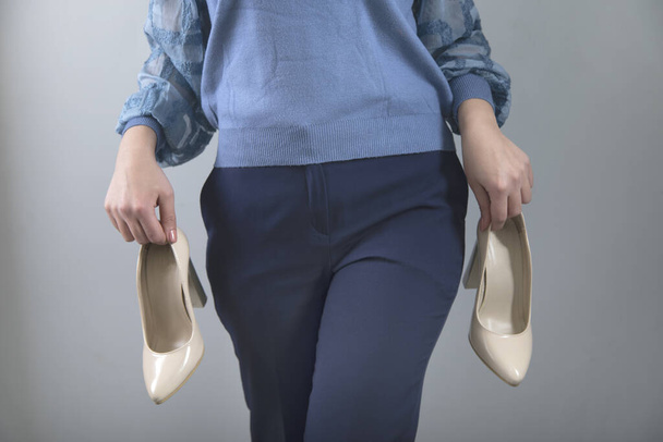 woman hand holding white shoes on grey background - Foto, Imagem