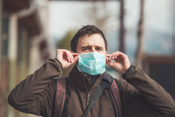 Young man outdoors putting on face mask. Corona virus  and flu season. - Foto, Imagem