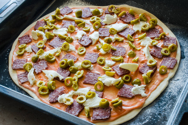 Zelf gemaakte rauwe pizza met salami, mozzarella, olijven en kaas. Sluitingsdatum - Foto, afbeelding