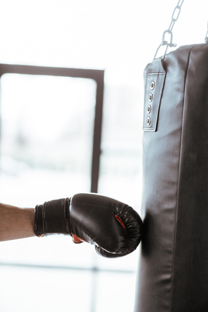 przycięty widok sportowca w bokserskiej rękawicy treningowej z workiem bokserskim   - Zdjęcie, obraz