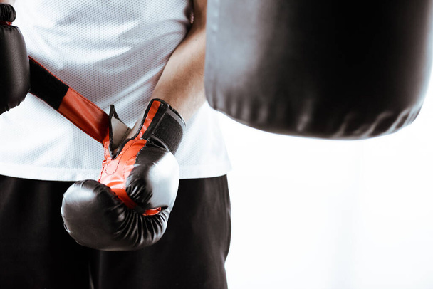 スポーツセンターで黒のボクシンググローブに触れるスポーツマンのクロップドビュー  - 写真・画像