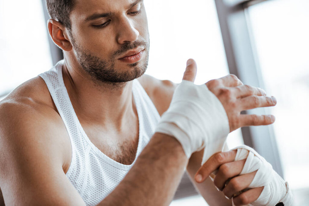 selective focus of sportsman wrapping hand in sports bandage  - Foto, Imagem