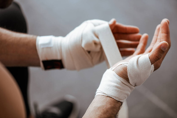 cropped view of man wrapping hand elastic sports bandage  - Photo, image