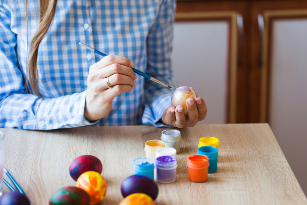 Праздники, ручная работа и концепция создания - девочка рисует пасхальное яйцо крупным планом
. - Фото, изображение