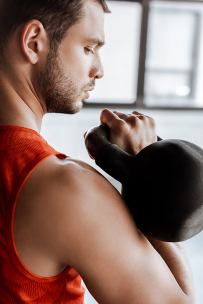 athletic sportsman exercising and looking at heavy dumbbell  - Photo, image