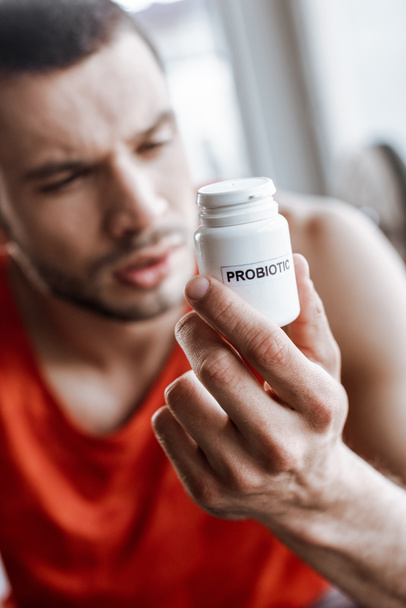 selective focus of sportsman holding bottle with probiotic lettering in gym  - Photo, Image
