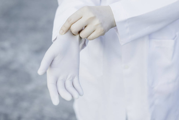 Lääkäri tai tiedemies käyttää valkoista takkia ja yllään valkoinen lateksi lehdot tai lääketieteellinen kumi lehdot valmis tekemään kokeilun laboratoriossa tai lääketieteellistä hoitoa
 - Valokuva, kuva