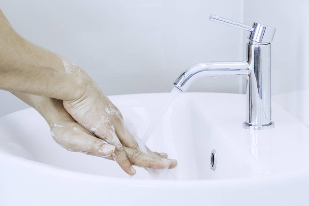 Mann Hände waschen oder reinigen mit Seifenschaum unter Leitungswasser auf der Toilette. Konzept guter Hygiene- und Coronavirus-Schutz - Foto, Bild
