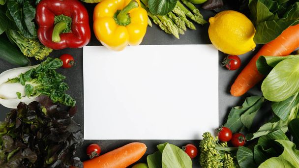 Frame of fresh organic vegetables background and white blank paper on table, Healthy food concept top view. - Photo, Image